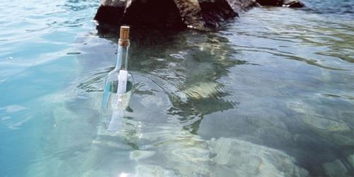 Photo of a letter in a bottle floating in water.